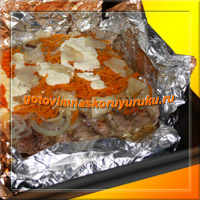 Фотография готового блюда: свиные ребрышки, запеченные в духовке с морковью и луком.